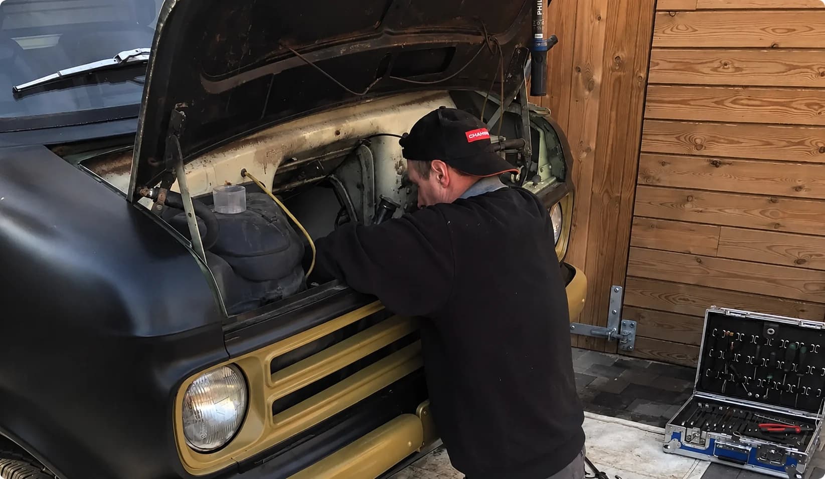 Filip werkt onder de motorkap van een klassieke Bedford